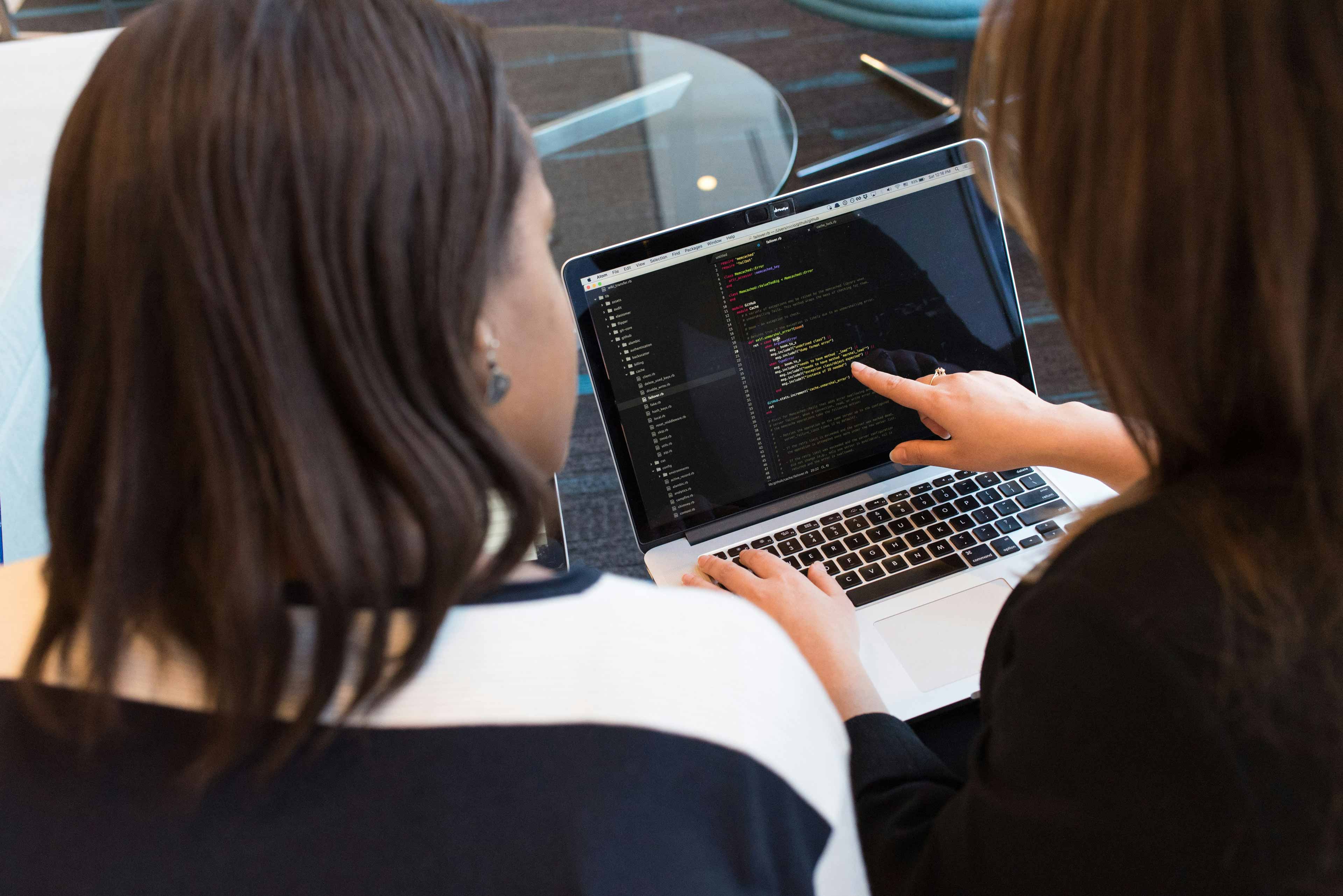 two developers troubleshooting a coding problem on a computer